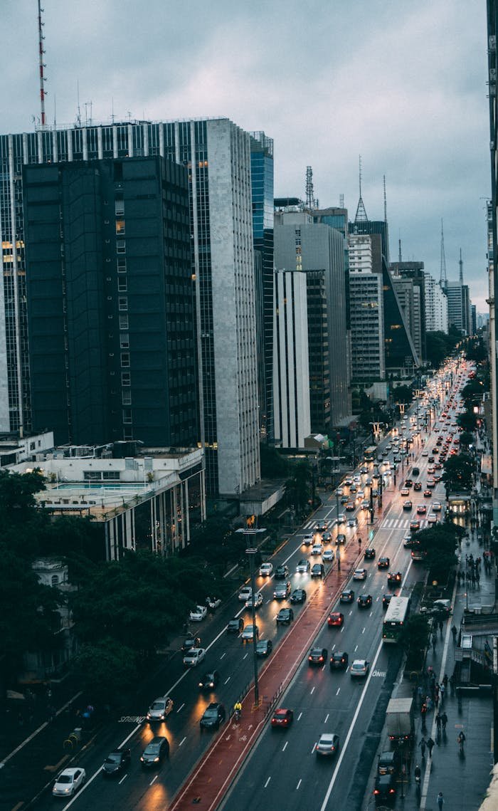 A lively urban scene of a city avenue with skyscrapers and evening traffic.